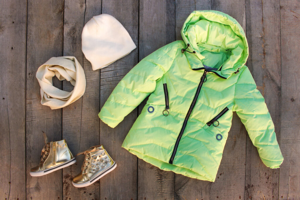 Children's winter clothes on old wooden background. Top vie